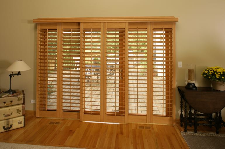 Faux wood shutters on sliding door connecting to outdoor porch.